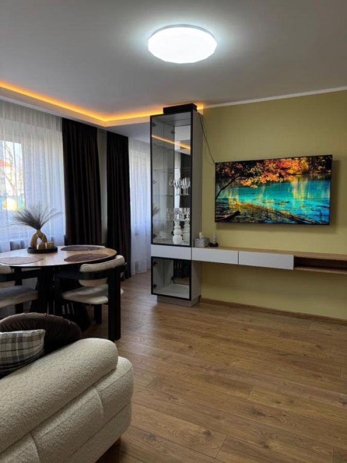 Svetainė su stikline vitrina ir pakabinama TV komoda baltais fasadais
